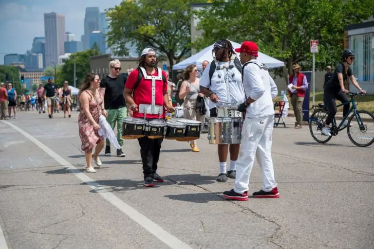 drumline performers chatting as they prepare for street festival performance